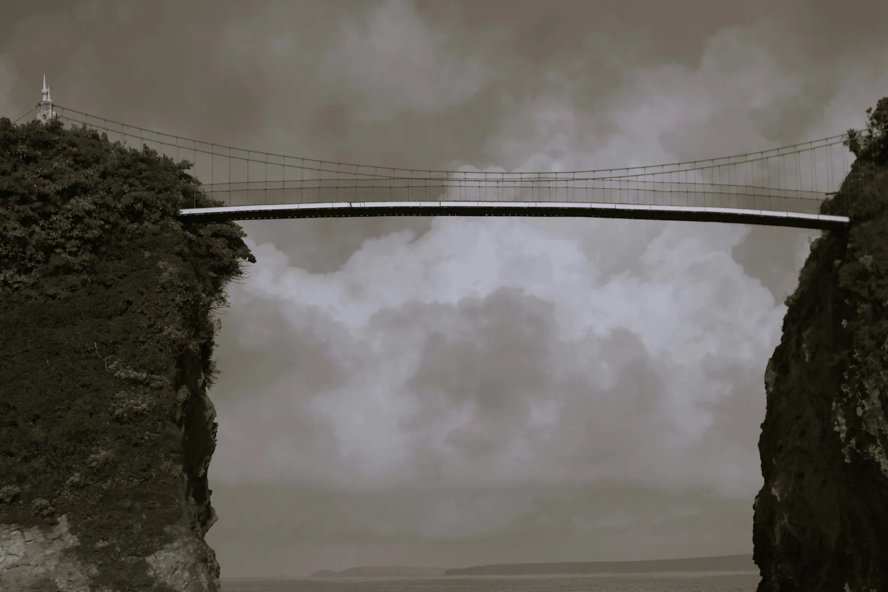 Schmale Brücke zwischen zwei Felsen unter grauem Himmel