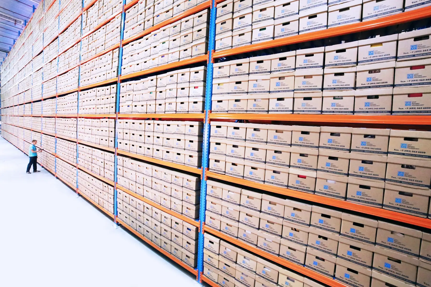 Lange Archivregale mit Kartons, davor eine einzelne Person