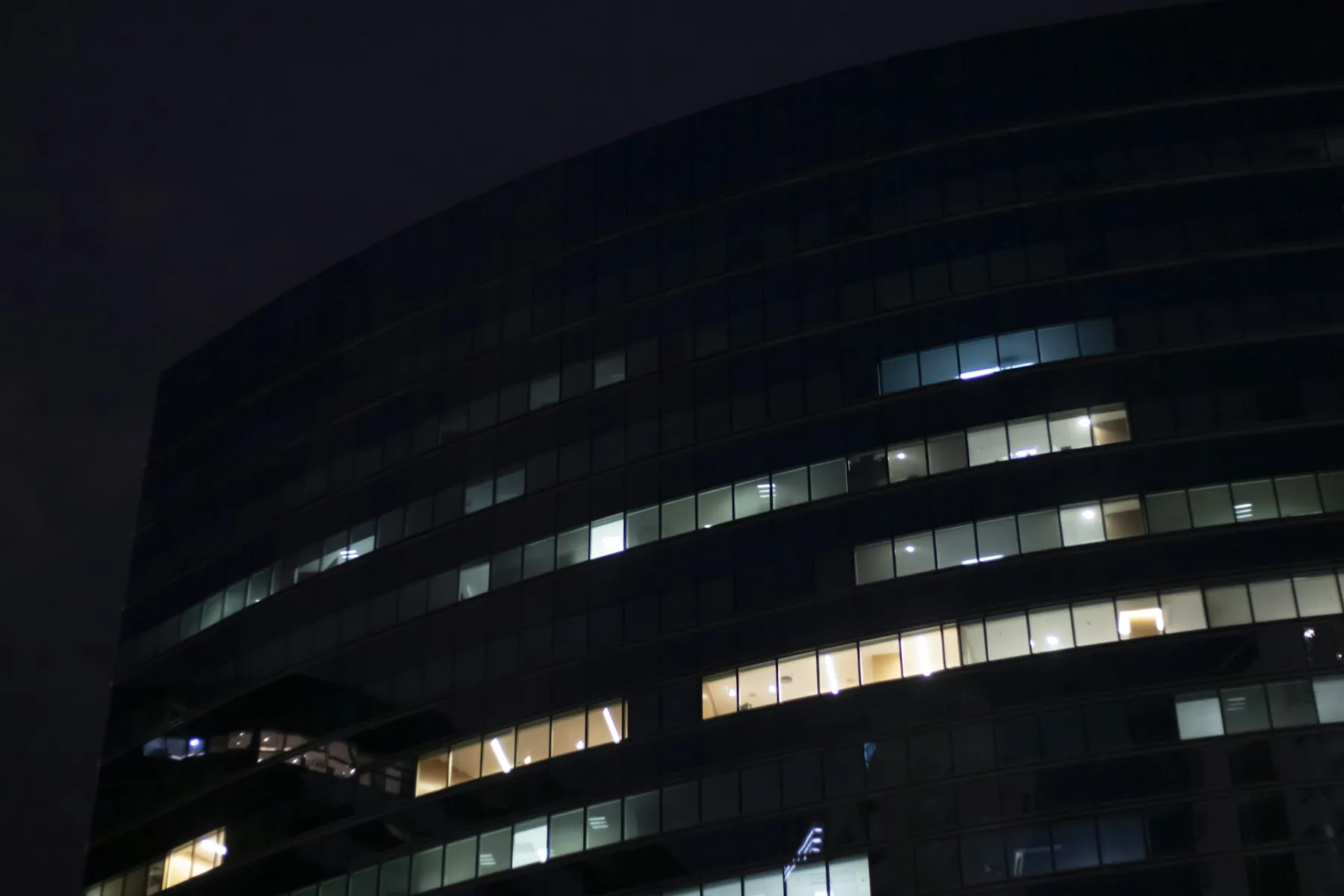 Bürogebäude bei Nacht, nur wenige Fenster sind beleuchtet