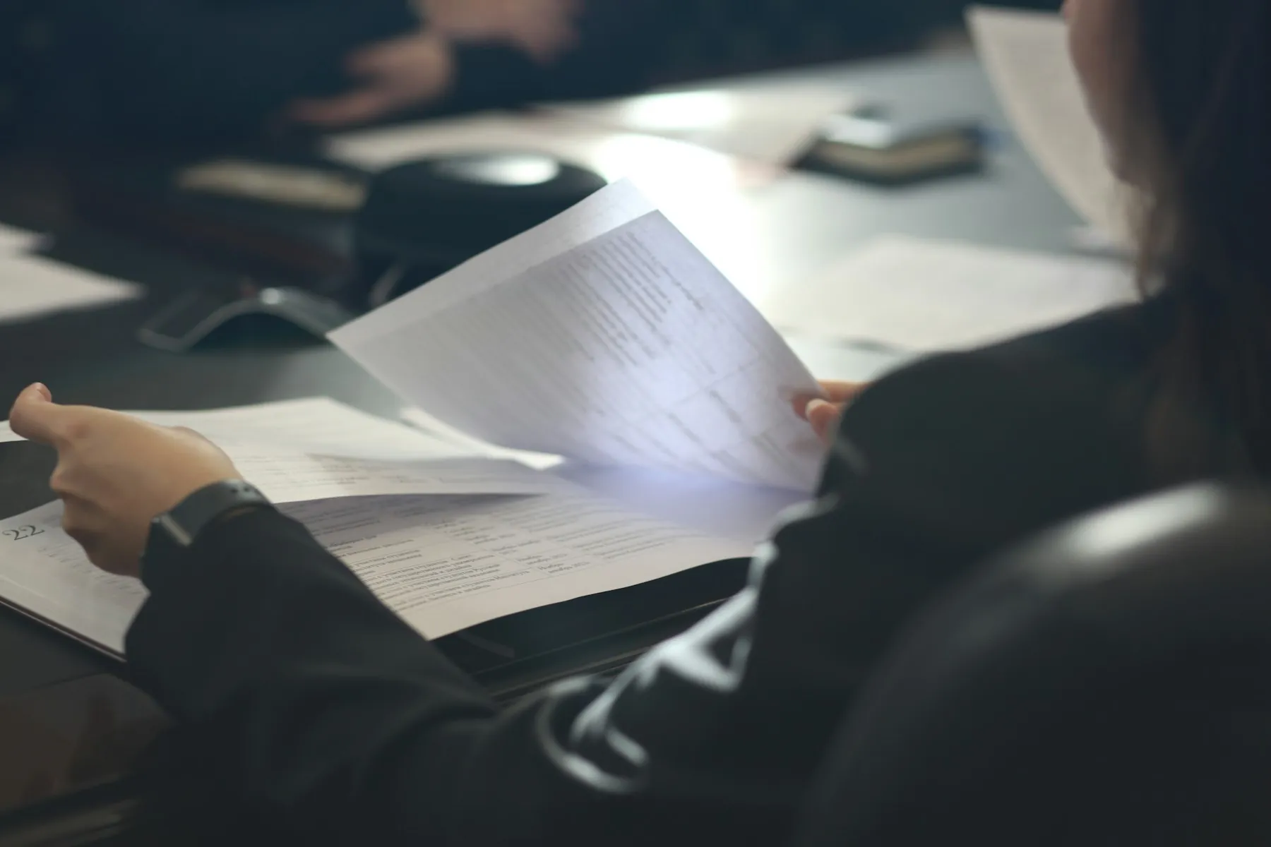 Hände mit einem Blatt Papier im Halbdunkel