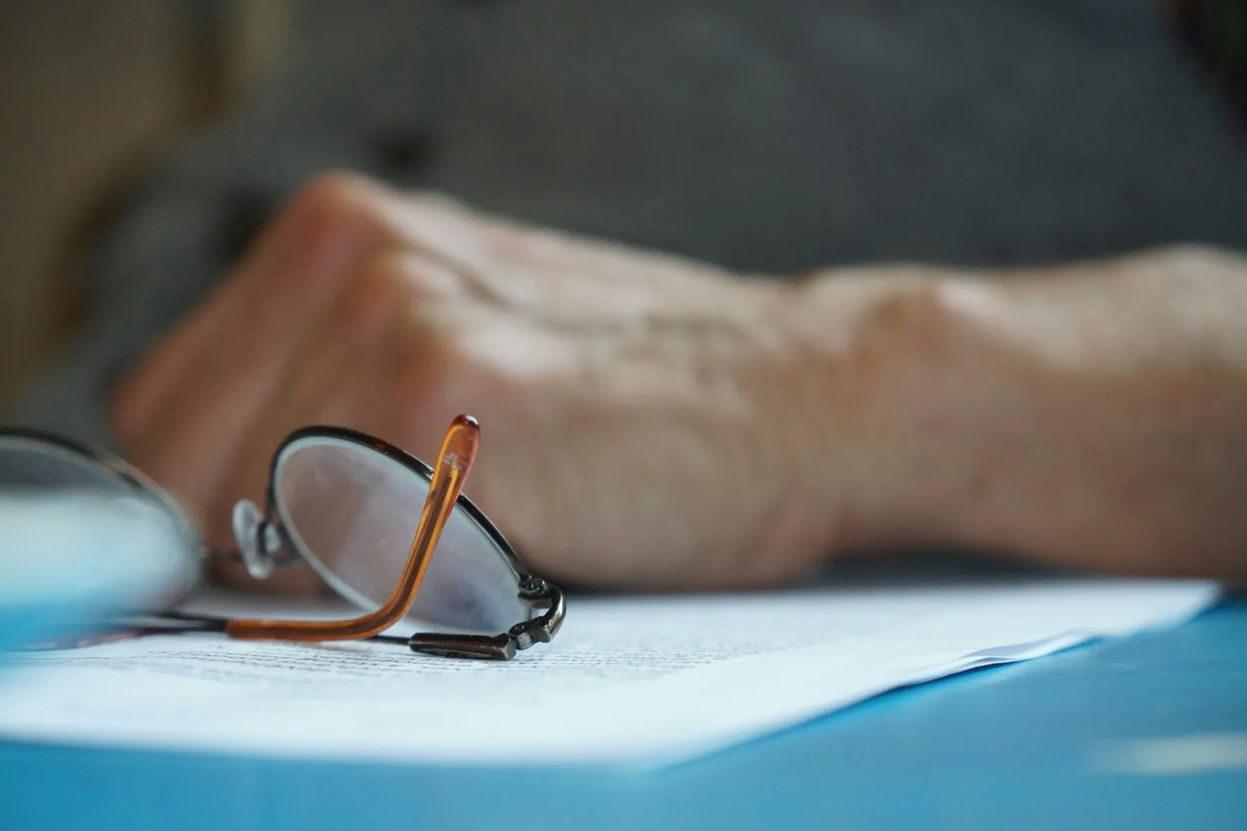 Hand und Brille auf Unterlagen
