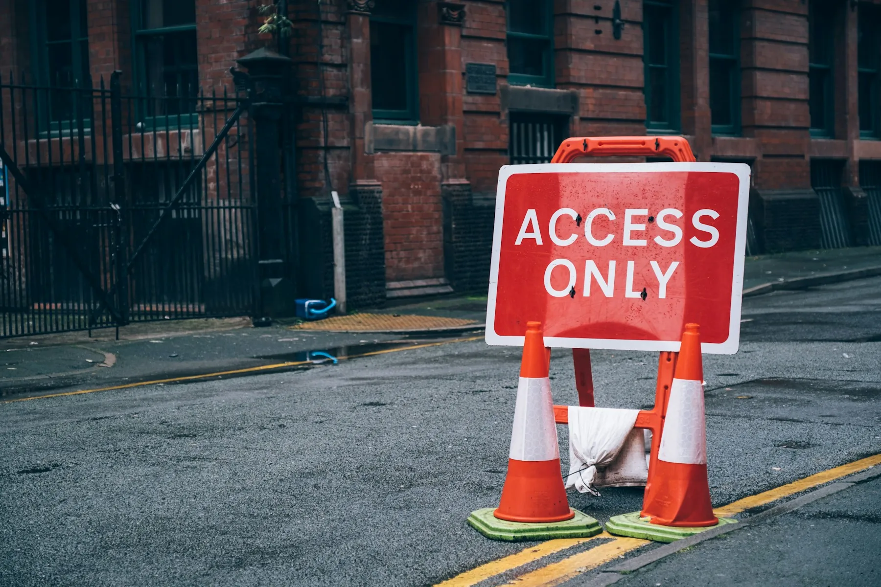 Absperrung mit Schild „Access only“ und Leitkegeln auf einer Straße